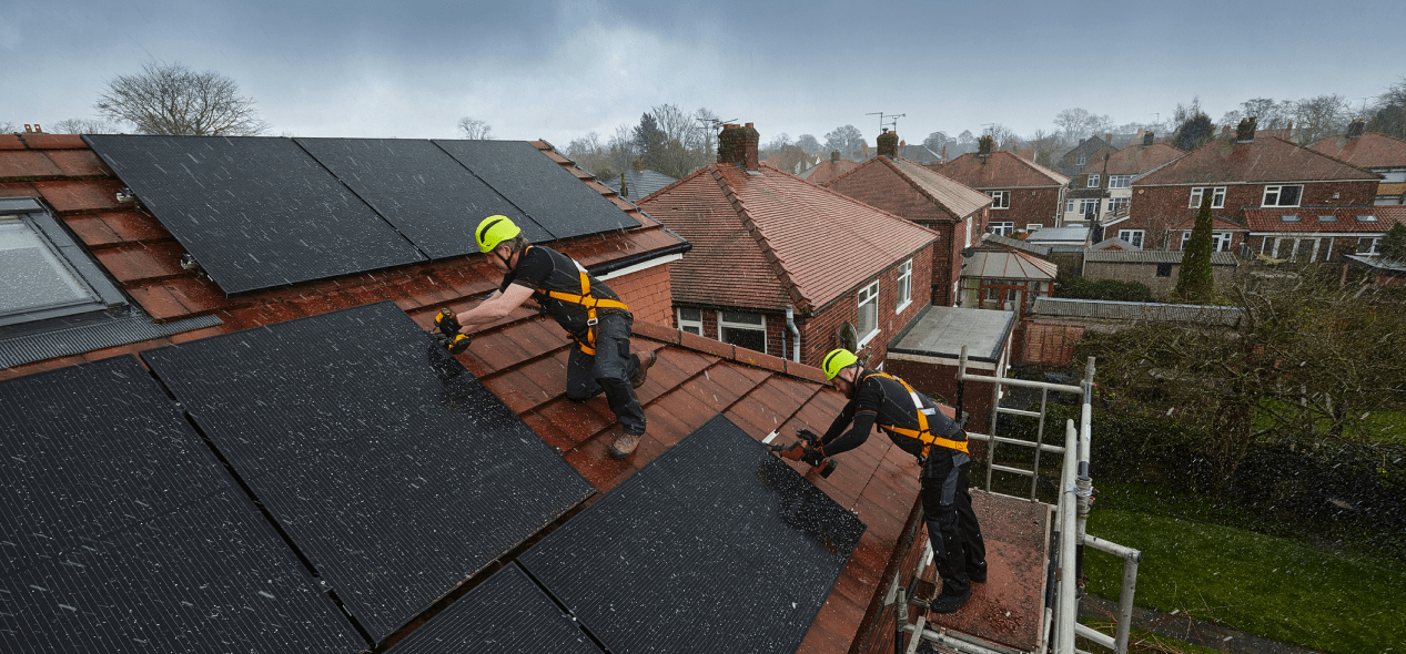 two construction workers installing solar panels on a roof