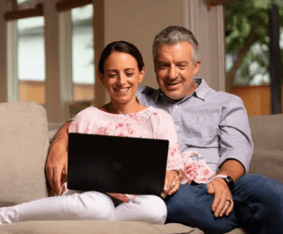 Happy couple on their laptop sit in their living room looking at Solar Lease